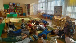Dzieci leżą na dywanie, prowadząca czyta bajkę.