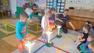 Troje dzieci prezentuje eksperyment z wykorzystaniem energii słonecznej.