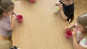 Dzieci przy stoliku wykonują ćwiczenia oddechowe z wykorzystaniem słomek