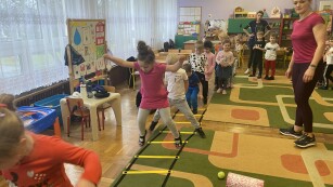 Dzieci przeskakują przez drabinkę gimnastyczną